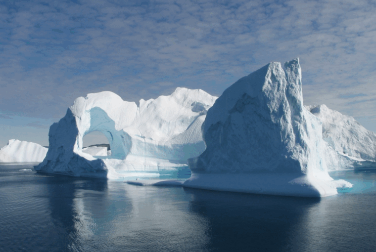 A colour photograph of a large iceberg floating in the sea off the coast of Greenland.