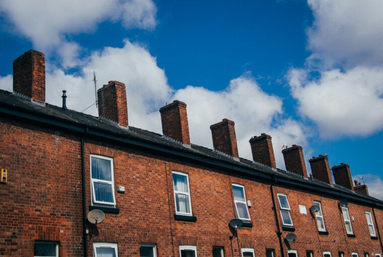 Photograph of a row of terraced houses below a blue sky with white, fluffy clouds